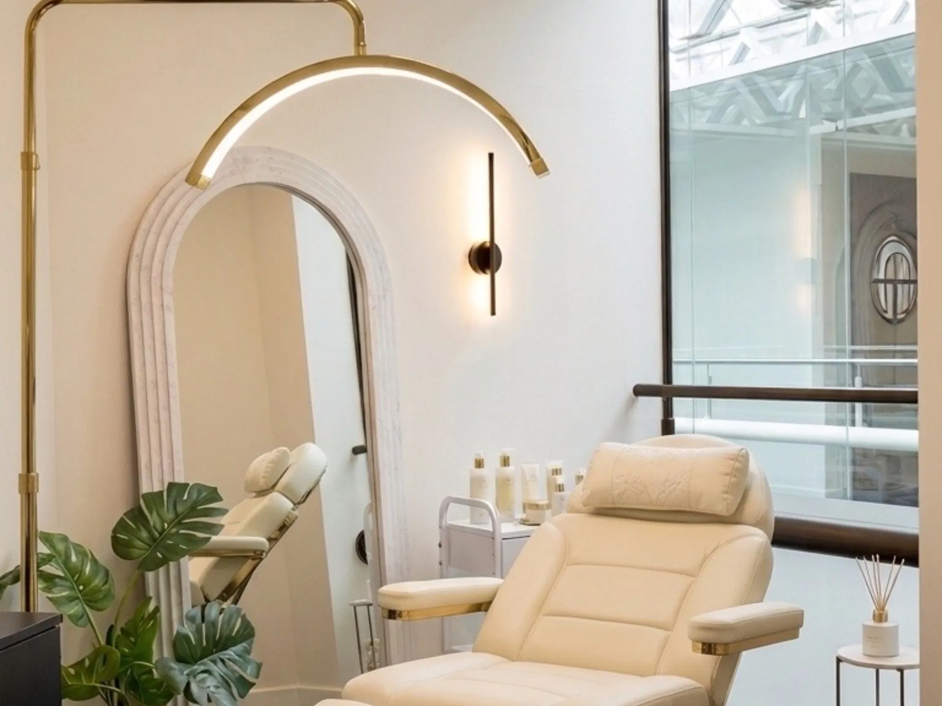 Buckingham Aesthetics treatment room with a cream treatment chair, arched mirror and gold light